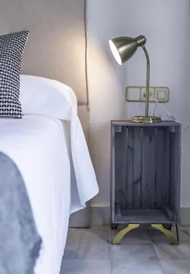 a lamp on a night stand next to a bed at Luminoso y acogedor apartamento en el centro in El Puerto de Santa María