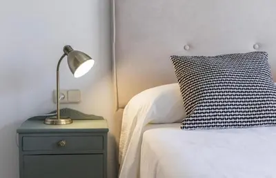 a lamp on a night stand next to a bed at Luminoso y acogedor apartamento en el centro in El Puerto de Santa María