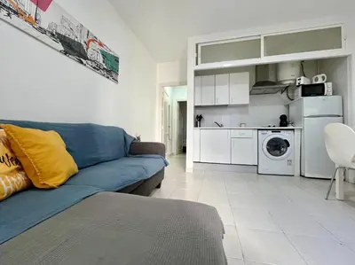 a living room with a blue couch and a kitchen at Apartamento Pescadores in Chiclana de la Frontera