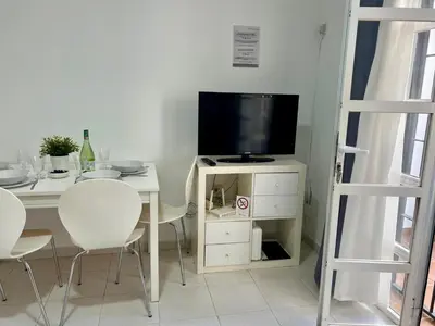 a living room with a table with a tv and chairs at Apartamento Pescadores in Chiclana de la Frontera
