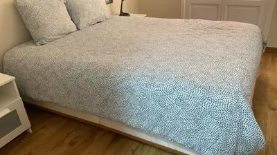 a bed with a blue and white comforter on it at Piso Palacio centro in El Puerto de Santa María