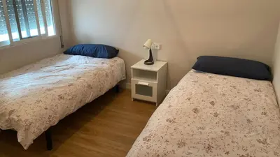 a bedroom with two beds and a night stand with a lamp at Piso Palacio centro in El Puerto de Santa María