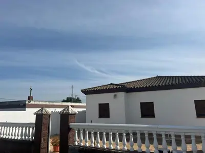 a white house with a fence next to a building at Sun and relaxation Book your paradise in Chiclana de la Frontera