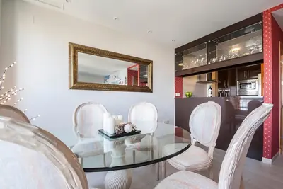 a dining room with a glass table and white chairs at Apartamento Vistabella in Cádiz