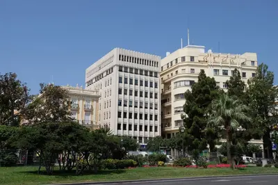 a tall white building with trees in front of a street at Apartamento Vistabella in Cádiz