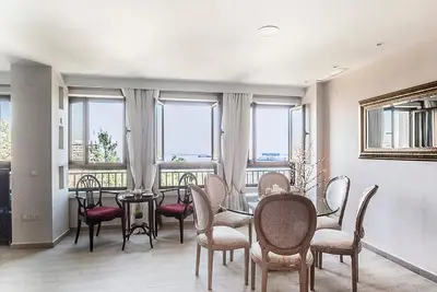 a dining room with a table and chairs and windows at Apartamento Vistabella in Cádiz