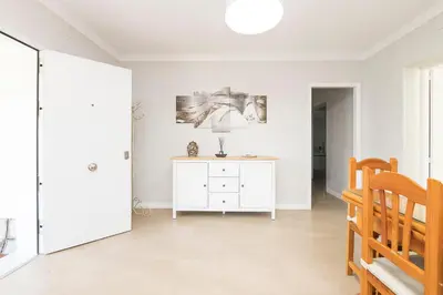 a white living room with a lamp on a dresser at Las Camelias in Chiclana de la Frontera