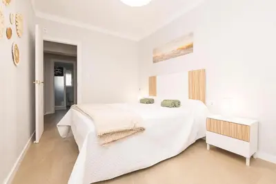 a white bedroom with a large white bed with towels on it at Las Camelias in Chiclana de la Frontera