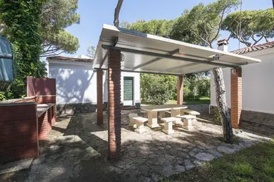 a picnic table and bench under a pavilion at Las Camelias in Chiclana de la Frontera