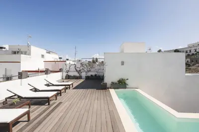 a balcony with chairs and a swimming pool on a building at Luxe Madre de Dios in Sanlúcar de Barrameda