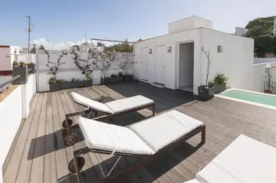 a deck with white chairs and a swimming pool at Luxe Madre de Dios in Sanlúcar de Barrameda