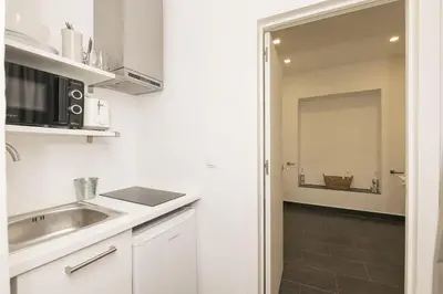 a white kitchen with a sink and a microwave at Luxe Madre de Dios in Sanlúcar de Barrameda