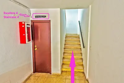 a stairway with a red arrow leading to a red door at Plaza España 3-bedroom central & bello apartamento in El Puerto de Santa María