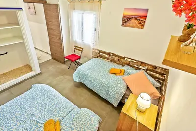 a bedroom with two beds and a red chair at Plaza España 3-bedroom central & bello apartamento in El Puerto de Santa María