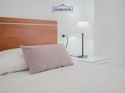 a bed with a pillow and a lamp on it at Piso Real Fernando in Sanlúcar de Barrameda
