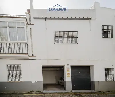 a white building with a garage and a sign on it at Casa Puerto Lucero in Sanlúcar de Barrameda