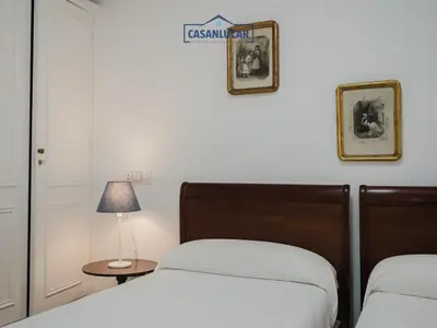 a bedroom with two beds and a table with a lamp at Casa Puerto Lucero in Sanlúcar de Barrameda