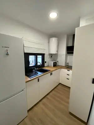 a kitchen with white cabinets and a laptop on the counter at Casa Mateo in Jedula