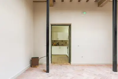 an empty room with a white wall and a kitchen at Taina La Merced Suite in Jerez de la Frontera