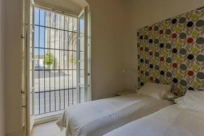 a bedroom with a bed and a large window at Taina La Merced Suite in Jerez de la Frontera
