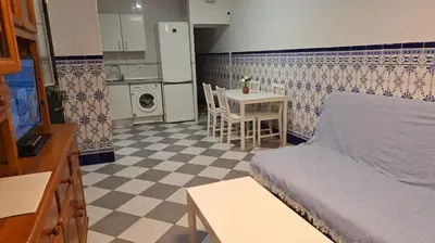 a bedroom with a bed and a table and a kitchen at La Marea in Chipiona