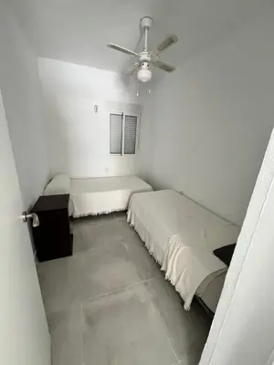 a white room with two beds and a ceiling fan at Casa Ianira in El Puerto de Santa María