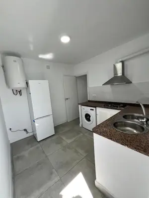 a white kitchen with a sink and a refrigerator at Casa Ianira in El Puerto de Santa María