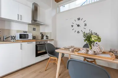a kitchen with a table and chairs and a clock on the wall at Taina Suite La Merced Primero Muro in Jerez de la Frontera