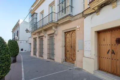 a building with a large wooden door on a street at Taina Suite La Merced Primero Muro in Jerez de la Frontera