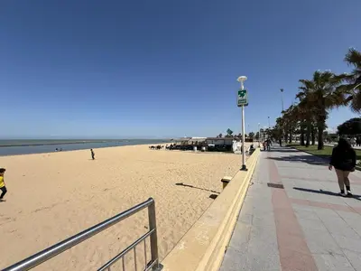 a beach with people walking on the sand and the ocean at Sousa by Staycare in Chipiona