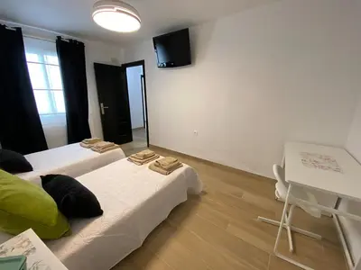 a room with two beds and a table and a desk at Apartmento Carmen Viejo, Centro in Sanlúcar de Barrameda