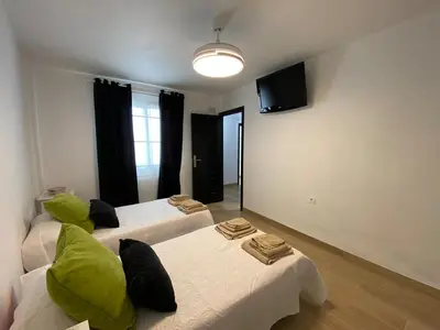 a room with two beds with green pillows at Apartmento Carmen Viejo, Centro in Sanlúcar de Barrameda