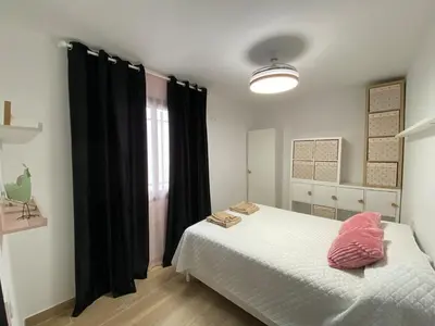 a bedroom with a bed with a pink pillow on it at Apartmento Carmen Viejo, Centro in Sanlúcar de Barrameda