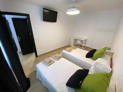 a room with two beds and a flat screen tv at Apartmento Carmen Viejo, Centro in Sanlúcar de Barrameda