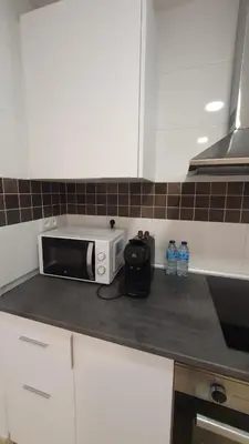 a kitchen counter with a microwave and two bottles of water at Apartamento Azalea in El Puerto de Santa María