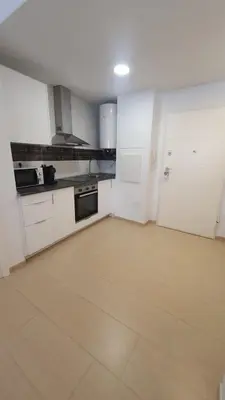a kitchen with white cabinets and a tile floor at Apartamento Azalea in El Puerto de Santa María