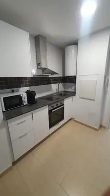 a small kitchen with white cabinets and a sink at Apartamento Azalea in El Puerto de Santa María