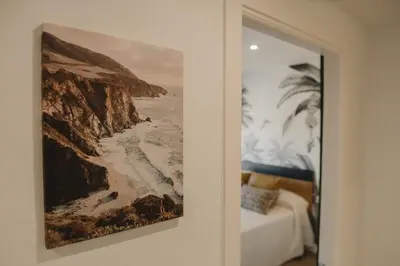 a painting of a beach on a wall next to a bed at Apartamento The River in El Puerto de Santa María