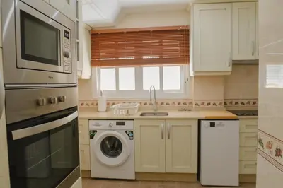 a kitchen with a washing machine and a microwave at Apartamento The River in El Puerto de Santa María