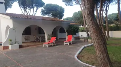 a patio with red chairs and a building at Pinos Verdes in Chiclana de la Frontera