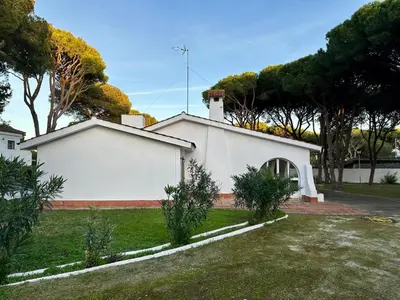 a white building in a yard with trees at Pinos Verdes in Chiclana de la Frontera