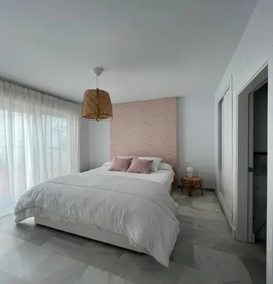 a white bedroom with a large bed with pink pillows at Charming house Costa Ballena in Rota