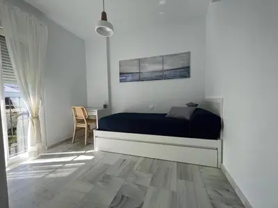 a white bedroom with a bed and a table at Charming house Costa Ballena in Rota