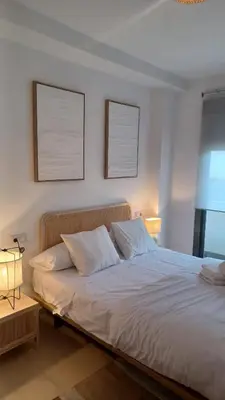 a bedroom with a white bed with two pictures on the wall at Apartamento Nuevo Céntrico El Puerto de Santa María in El Puerto de Santa María