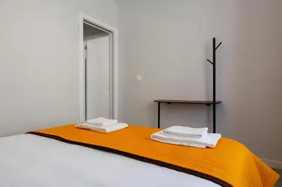 a bedroom with a bed with an orange blanket and a table at Apartamento San Jose Grupo AC Gestion in Cádiz