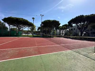 a tennis court with a net and some trees at La Almadraba segunda Pista in Chiclana de la Frontera