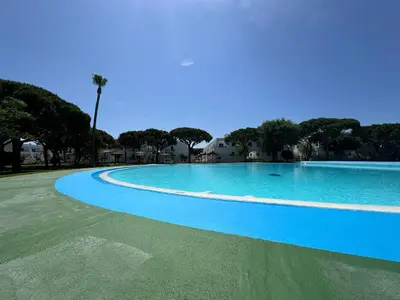 a large blue swimming pool with trees in the background at La Almadraba segunda Pista in Chiclana de la Frontera
