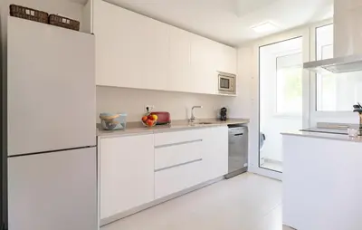 a white kitchen with white cabinets and a window at Beautiful Apartment In Chipiona in Chipiona