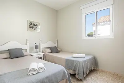a bedroom with two beds and a window at Arenas 65 in Chiclana de la Frontera