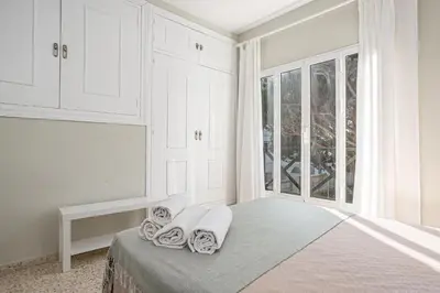 a white bedroom with a bed and a window at Arenas 65 in Chiclana de la Frontera